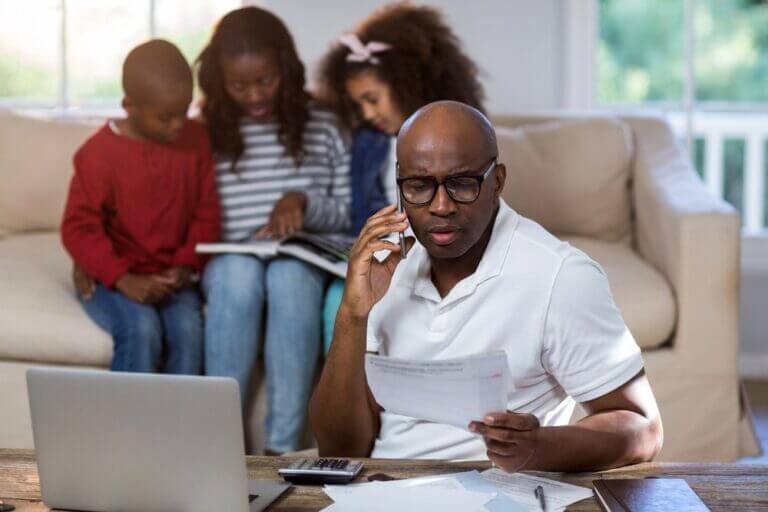 Man talking on mobile phone while checking bills at home.jpeg