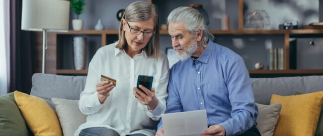 Man and woman on couch using cell phone to use digital communications and payment options with Nordis' omnichannel collects.