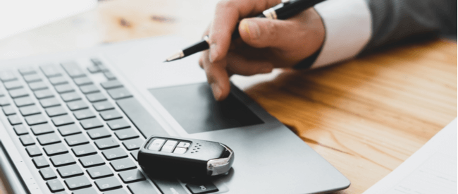 Man's hand using computer to send Auto Finance Customer Communications